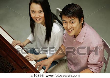 Stock Image - Couple at a piano, looking up. Fotosearch