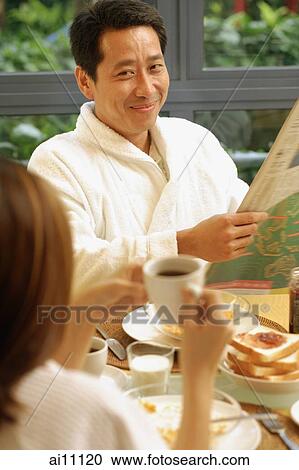 Couple at breakfast table, man holding newspaper View Large Photo Image Stock Image - Couple at breakfast table, man holding newspaper. Fotosearch