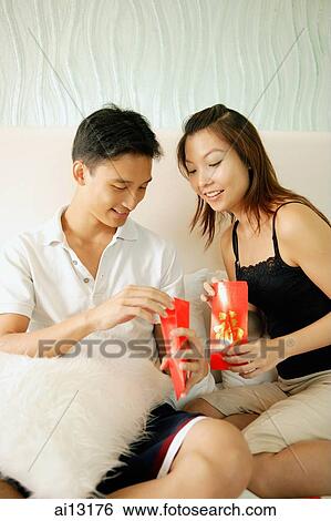 Couple at home looking inside red envelopes View Large Photo Image Stock Photograph - Couple at home looking inside red envelopes. Fotosearch