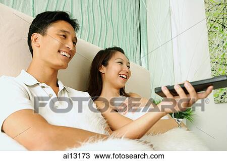 Couple at home, man holding remote control View Large Photo Image Stock Image - Couple at home, man holding remote control. Fotosearch
