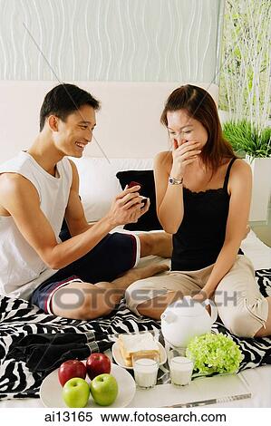 Couple at home, man holding ring box, woman with hand over mouth View Large Photo Image Stock Photography - Couple at home, man holding ring box, woman with hand over mouth. Fotosearch