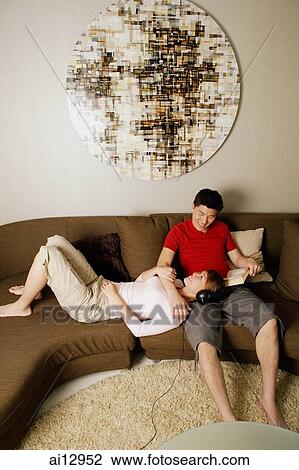 Stock Image - Couple at home, woman lying on man's lap. Fotosearch