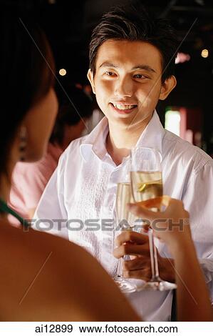 Couple at night club, holding champagne glasses, man facing woman View Large Photo Image Stock Photo - Couple at night club, holding champagne glasses, man facing woman. Fotosearch