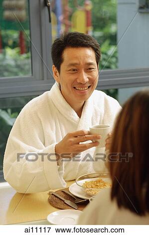 Couple facing each other, holding cups of coffee, man smiling View Large Photo Image Stock Photo - Couple facing each other, holding cups of coffee, man smiling. Fotosearch