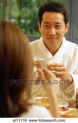 Couple facing each other, holding cups of coffee View Large Photo Image Stock Photograph - Couple facing each other, holding cups of coffee. Fotosearch