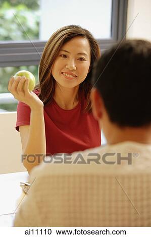 Couple facing each other, woman holding an apple View Large Photo Image Stock Image - Couple facing each other, woman holding an apple. Fotosearch