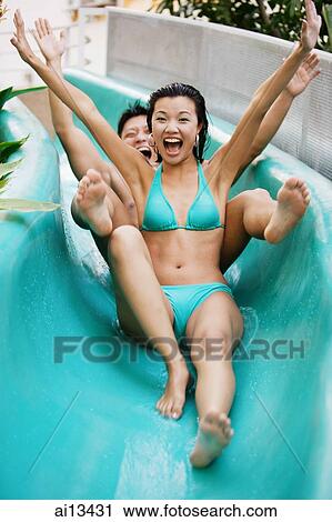 Stock Image - Couple going down water slide. Fotosearch