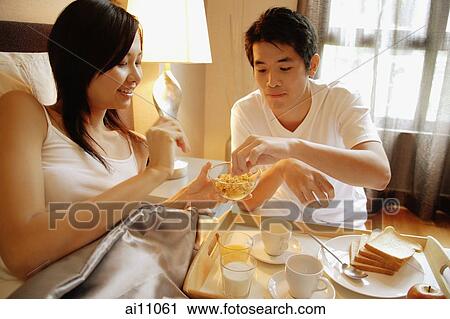 Stock Image - Couple having breakfast in bed. Fotosearch