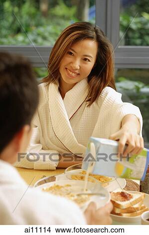 Couple having breakfast, woman pouring milk. View Large Photo Image Picture - Couple having breakfast, woman pouring milk.. Fotosearch