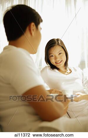 Couple having coffee, sitting on sofa, woman looking at camera View Large Photo Image Stock Image - Couple having coffee, sitting on sofa, woman looking at camera. Fotosearch