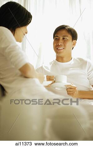 Couple having coffee, sitting on sofa. View Large Photo Image Stock Image - Couple having coffee, sitting on sofa.. Fotosearch