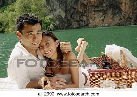 Couple having picnic by a lake, looking at camera View Large Photo Image Stock Image - Couple having picnic by a lake, looking at camera. Fotosearch