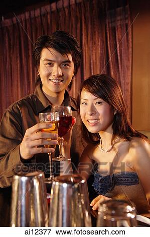 Couple holding drinks looking at camera View Large Photo Image Stock Photo - Couple holding drinks looking at camera. Fotosearch