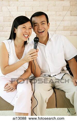 Stock Photo - Couple holding microphone, singing. Fotosearch