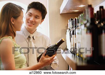 Couple holding wine bottle, looking at each other View Large Photo Image Stock Image - Couple holding wine bottle, looking at each other. Fotosearch