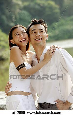 Couple hugging, looking up, smiling View Large Photo Image Stock Photograph - Couple hugging, looking up, smiling. Fotosearch