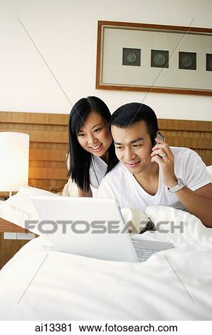 Couple in bedroom looking at laptop, man using mobile phone View Large Photo Image Stock Image - Couple in bedroom looking at laptop, man using mobile phone. Fotosearch