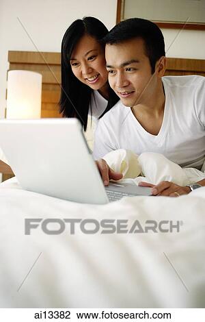 Couple in bedroom looking at laptop View Large Photo Image Stock Image - Couple in bedroom looking at laptop. Fotosearch