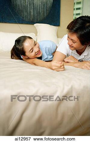 Couple in bedroom, lying on bed View Large Photo Image Stock Photo - Couple in bedroom, lying on bed. Fotosearch