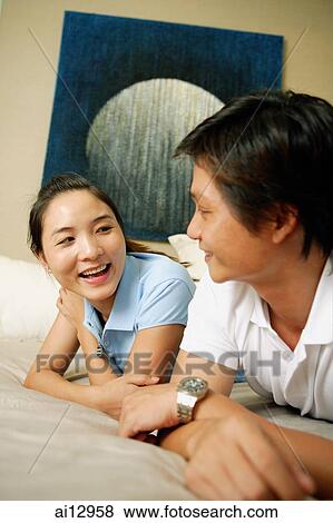 Couple in bedroom, lying on front, side by side View Large Photo Image Stock Photo - Couple in bedroom, lying on front, side by side. Fotosearch