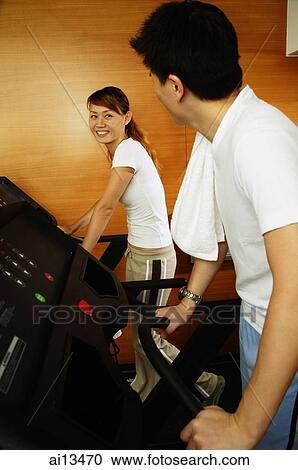 Couple in gym using treadmill, looking at each other View Large Photo Image Stock Image - Couple in gym using treadmill, looking at each other. Fotosearch