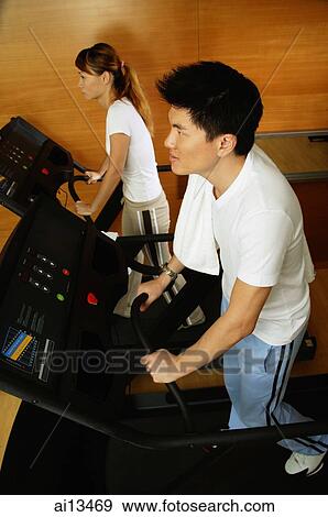 Couple in gym using treadmill View Large Photo Image Stock Photo - Couple in gym using treadmill. Fotosearch