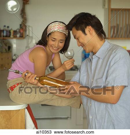 Couple in kitchen, looking at wine bottle View Large Photo Image Stock Image - Couple in kitchen, looking at wine bottle. Fotosearch