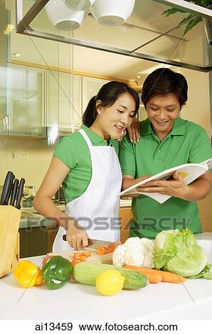 Couple in kitchen, looking through cookbook View Large Photo Image Stock Photo - Couple in kitchen, looking through cookbook. Fotosearch
