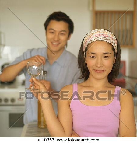 Couple in kitchen, man opening wine bottle, woman holding wine glass View Large Photo Image Stock Photo - Couple in kitchen, man opening wine bottle, woman holding wine glass. Fotosearch