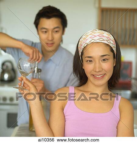 Couple in kitchen, man opening wine bottle, woman holding wine glass View Large Photo Image Stock Photograph - Couple in kitchen, man opening wine bottle, woman holding wine glass. Fotosearch