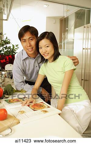 Stock Image - Couple in kitchen, side by side, looking at camera. Fotosearch