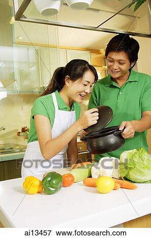 Couple in kitchen, woman lifting lid of pot and looking in View Large Photo Image Stock Photo - Couple in kitchen, woman lifting lid of pot and looking in. Fotosearch