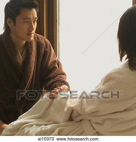 Stock Image - Couple in robes, looking at window. Fotosearch