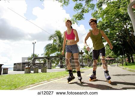 Couple inline skating at park, low angle view View Large Photo Image Stock Photo - Couple inline skating at park, low angle view. Fotosearch