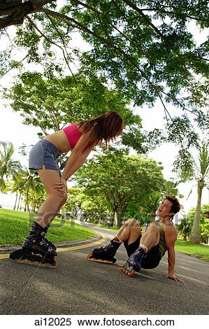 Couple inline skating at park, man on floor View Large Photo Image Stock Photography - Couple inline skating at park, man on floor. Fotosearch