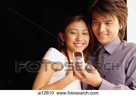 Couple looking at mobile phone, low angle view View Large Photo Image Stock Image - Couple looking at mobile phone, low angle view. Fotosearch
