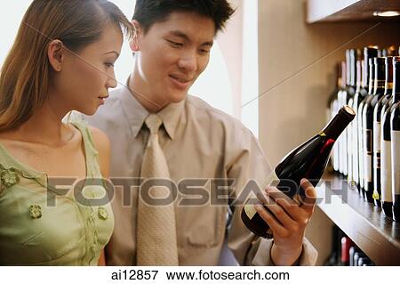 Stock Photo - Couple looking at wine bottle. Fotosearch