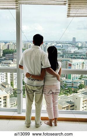 Couple looking out the window, arms around each other View Large Photo Image Stock Photo - Couple looking out the window, arms around each other. Fotosearch