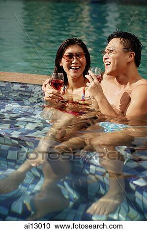 Couple lounging in pool, drinking wine View Large Photo Image Stock Image - Couple lounging in pool, drinking wine. Fotosearch