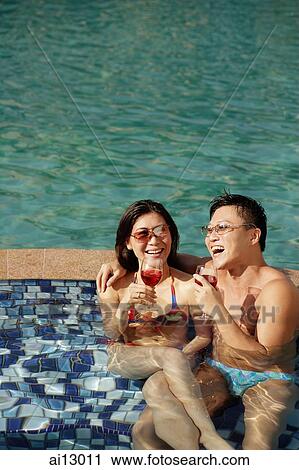 Couple lounging in pool, drinking wine View Large Photo Image Stock Image - Couple lounging in pool, drinking wine. Fotosearch