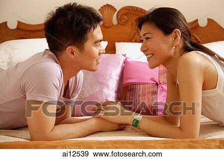 Stock Photo - Couple lying in bed, facing each other. Fotosearch