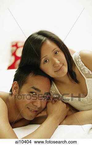 Couple on bed, looking at camera View Large Photo Image Picture - Couple on bed, looking at camera. Fotosearch