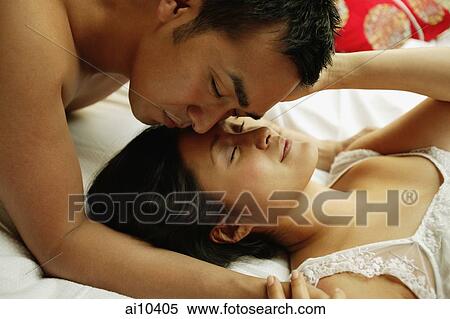 Couple on bed, man kissing woman's forehead View Large Photo Image Stock Photography - Couple on bed, man kissing woman's forehead. Fotosearch