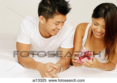 Couple on bed, woman holding gift box View Large Photo Image Stock Photography - Couple on bed, woman holding gift box. Fotosearch