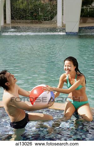 Couple on edge of pool fighting for inflatable ball View Large Photo Image Stock Photograph - Couple on edge of pool fighting for inflatable ball. Fotosearch
