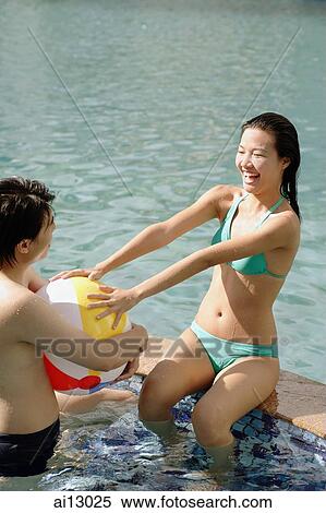Couple on edge of pool holding inflatable ball View Large Photo Image Stock Photography - Couple on edge of pool holding inflatable ball. Fotosearch