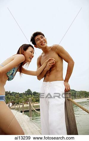 Couple on jetty, holding hands and laughing View Large Photo Image Stock Photo - Couple on jetty, holding hands and laughing. Fotosearch