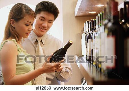 Couple reading label on wine bottle View Large Photo Image Stock Photo - Couple reading label on wine bottle. Fotosearch