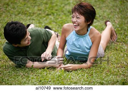 Couple side by side on the grass, laughing View Large Photo Image Stock Photo - Couple side by side on the grass, laughing. Fotosearch