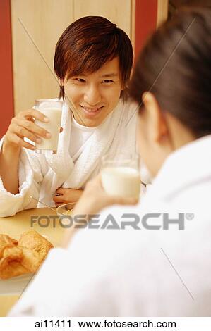 Couple sitting across each other drinking milk View Large Photo Image Stock Image - Couple sitting across each other drinking milk. Fotosearch